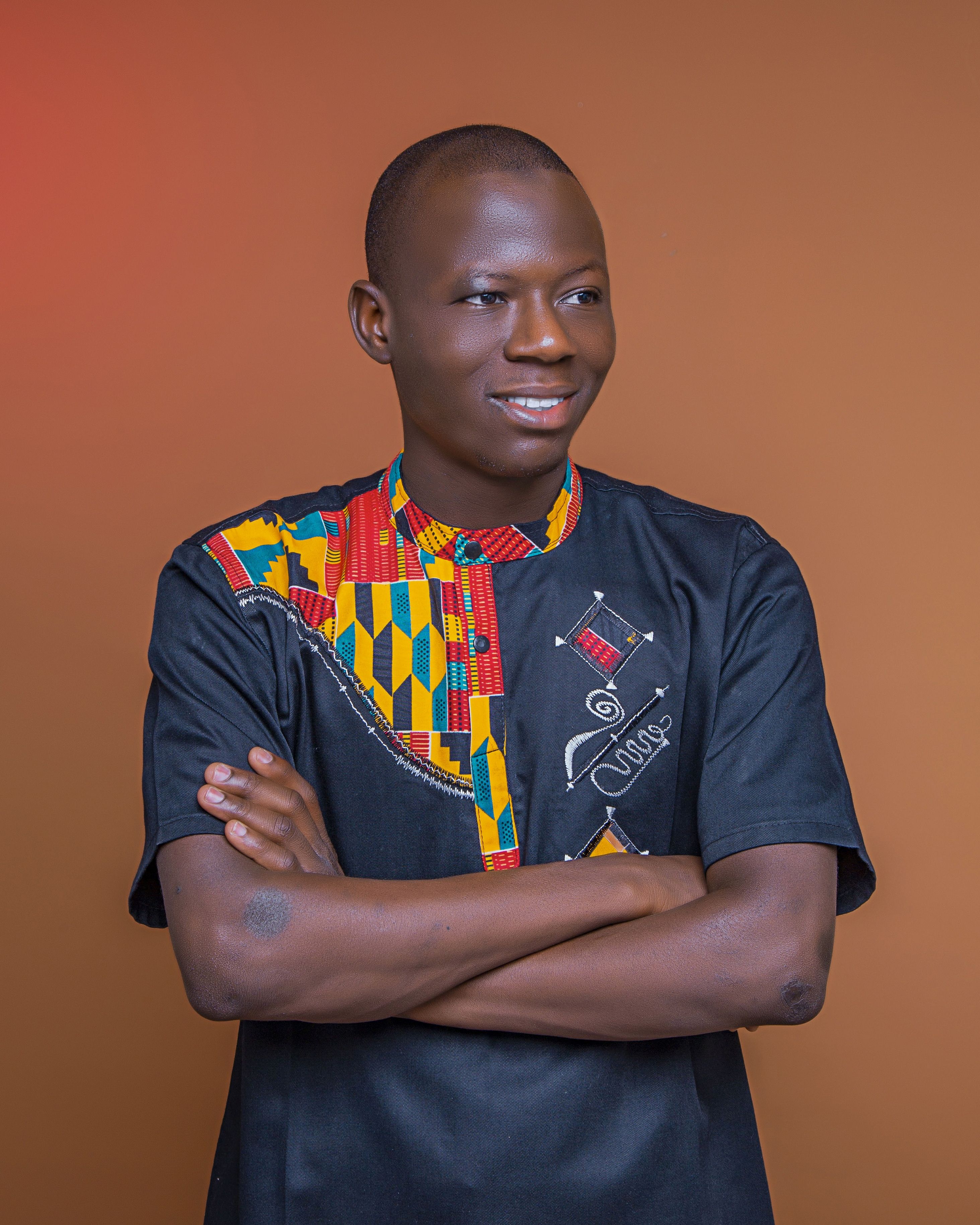 Portrait of a confident African man wearing colorful traditional attire against a solid background.